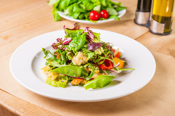Fresh green salad with spinach,arugula,romaine, lettuce, beet leaves, bell pepper and croutons on the wooden served table. Healthy vegetarian food. Selective focus, copy space.