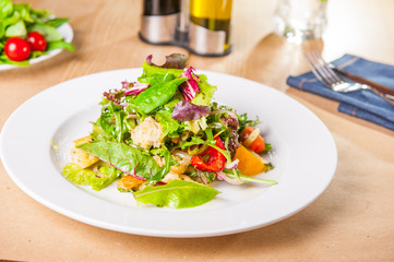 Fresh green salad with spinach,arugula,romaine, lettuce, beet leaves, bell pepper and croutons on the wooden served table. Healthy vegetarian food. Selective focus, copy space.
