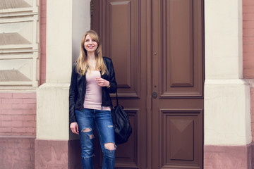 Nice blonde girl standing in the street near the building