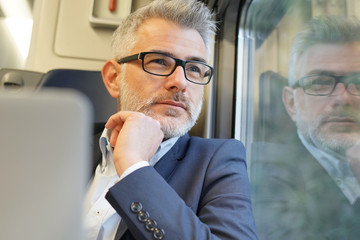 Businessman sitting on a train, looking by window