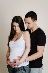 Image of husband standing and holding belly of pregnant wife hands. Woman, girl and loving handsome man hugging tummy at home. Loving Couple. Parenthood concept. Baby Shower. Family photo.