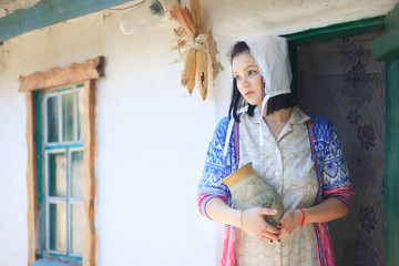 Woman on the background of a retro rural home with a jug in her hands.