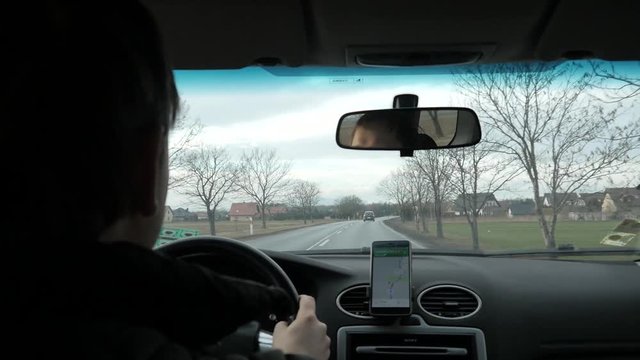 Man drives a Car on a Country Road, use Mobile app Google Maps