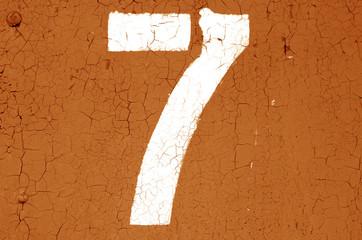 Number 7 in stencil on metal wall in orange tone.