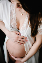 Pregnant Woman hold hands round stomach, girl embraces a round belly. Standing sideways. Maternity concept. Close up. nine months. Baby Shower.