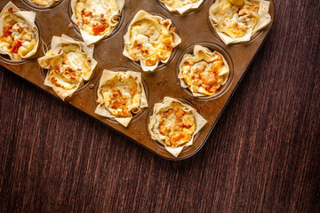 French cuisine concept. Mini cake Kish from pumpkin and goat cheese with filo dough. Cupcake baking dish. European appetizer to white wine. Top view, copy space
