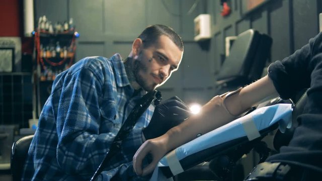 Male artist in the process of making a tattoo in his salon