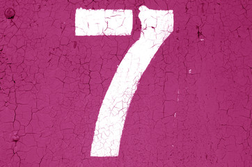 Number 7 in stencil on metal wall in pink tone.