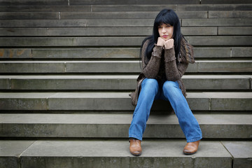 lonely young woman sitting on steps outside