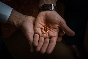 Groom holding wedding rings on the palm, the groom in a blue suit, groom holding wedding rings, groom's hand holding a ring, wedding ring in groom hand