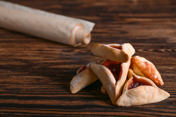 Hamantaschen and the Scroll of Esther on wooden table. Purim celebration