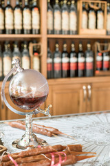 Glass carafe in the form of the globe with brandy on counter of a liquor store.