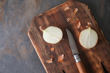 Cutting board with raw onion and knife on grey table