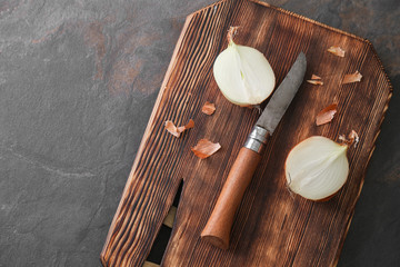 Fototapeta na wymiar Cutting board with raw onion and knife on grey table