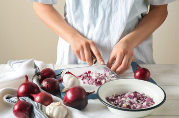 Obraz na płótnie Canvas Woman cutting raw onion on table