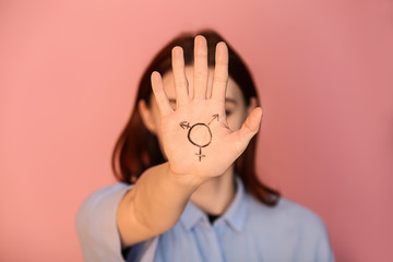 Woman with drawn symbol of transgender on her palm against color background