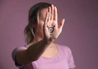 Woman with drawn symbol of transgender on her palm against color background