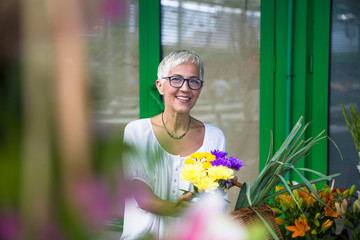 Charrming senior woman buying  flowers on  market