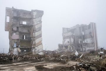 The remains of concrete fragments of gray stones on the background of the destroyed building in a...