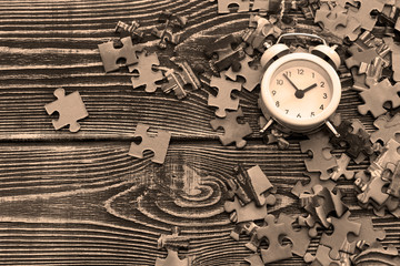 alarm clock, jigsaw puzzle on wooden background. puzzle game, leisure.