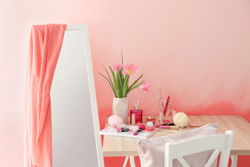 Dressing table with set of cosmetics near color wall