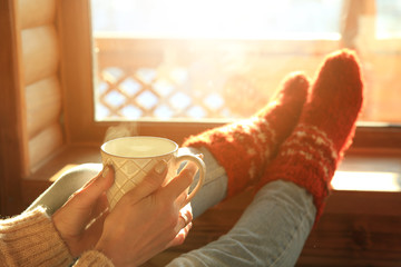 Woman drinking hot coffee near window in morning
