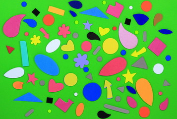 A color image of an array of shapes in many colors on with a green background.