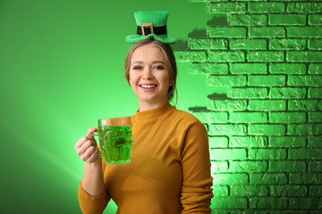 Beautiful young woman with green hat and mug of beer on color background. St. Patrick's Day...