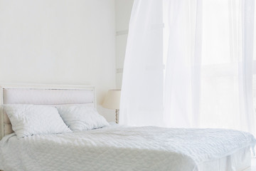 Abstract room with white bed, white walls and window with white curtain. Bedroom apartment