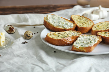 Plate with tasty cut garlic bread on table