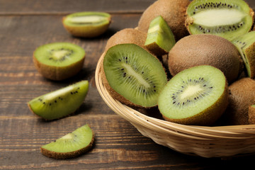 Delicious ripe many kiwi fruit and kiwi in a cut on a brown wooden table.
