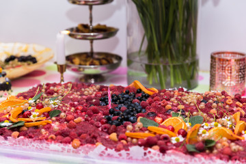 cake for a one-year anniversary celebration; home baked cake from natural, ecological ingredients, topped with berries and oranges picked up in the garden