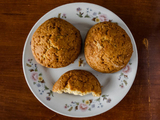 Homemade biscuits in a white plate on a dark table. One cookie cracked in half.