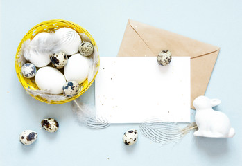 Blank greeting card, kraft envelope. Easter eggs in the basket. Flat lay, top view.
