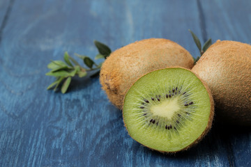 Delicious ripe many kiwi fruit and kiwi in a cut on a blue wooden table. close-up.