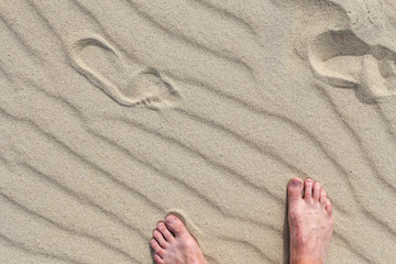 Footsteps in the sand and male feet. On Parnidis sand dune - popular tourist point in Lithuania. Located in Nida, in Curonian Spit between lagoon and baltic sea.