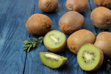 Delicious ripe many kiwi fruit and kiwi in a cut on a blue wooden table.