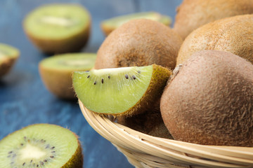 Delicious ripe many kiwi fruit and kiwi in a cut on a blue wooden table. close-up.