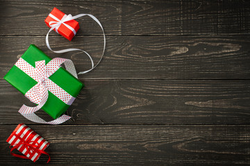 Fototapeta premium Festive background, gift boxes and ribbons on a brown wooden background, Valentine's Day or Christmas or birthday