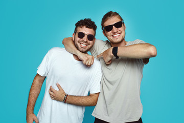 Two young hipster men have good relationship and truthful friendship, embarce each other and smile...