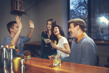 Photo of joyful friends in the bar or at pub communicating with each other