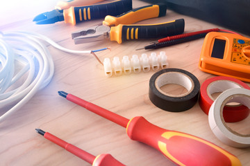 Composition of tools for electrical repairs on wooden table elevated