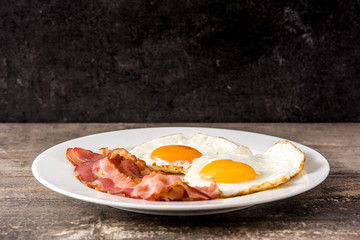 Fried eggs and bacon for breakfast on wooden table. 