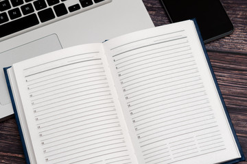 Opened clean business notebook and laptop. Business notebook for record important events and meetings with business partners on the wooden table