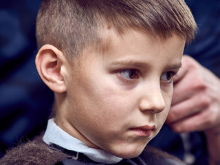 Boy  getting hairstyle in barbershop in London.