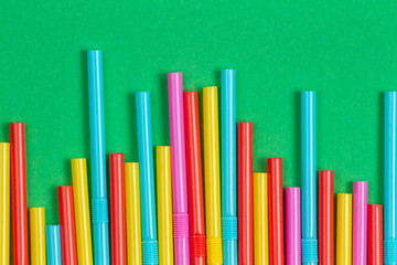 Multicolored cocktail tubes straws on green background