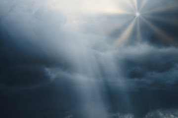 Fototapeta premium photograph of a cloudy sky with lead clouds and dim light hitting the clouds, and the bright rays of the sun from the clouds with a bird
