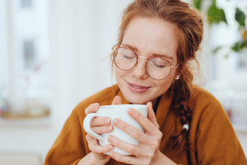 Girl in glasses enjoying hot beverage in cup