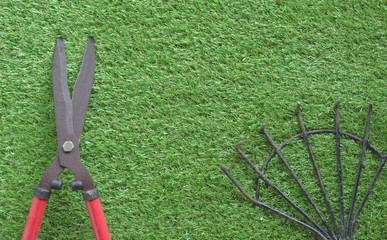 Large grass cutting scissors, red handle, steel rake on grass