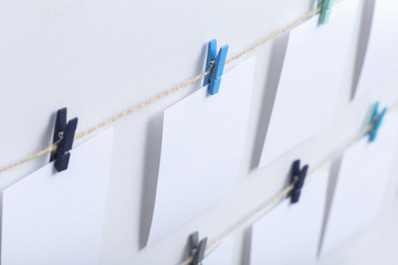 blank white cards hanging on colored clothespins on a thread on a white background, a template for a photo collage, a concept of memories and a photo industry